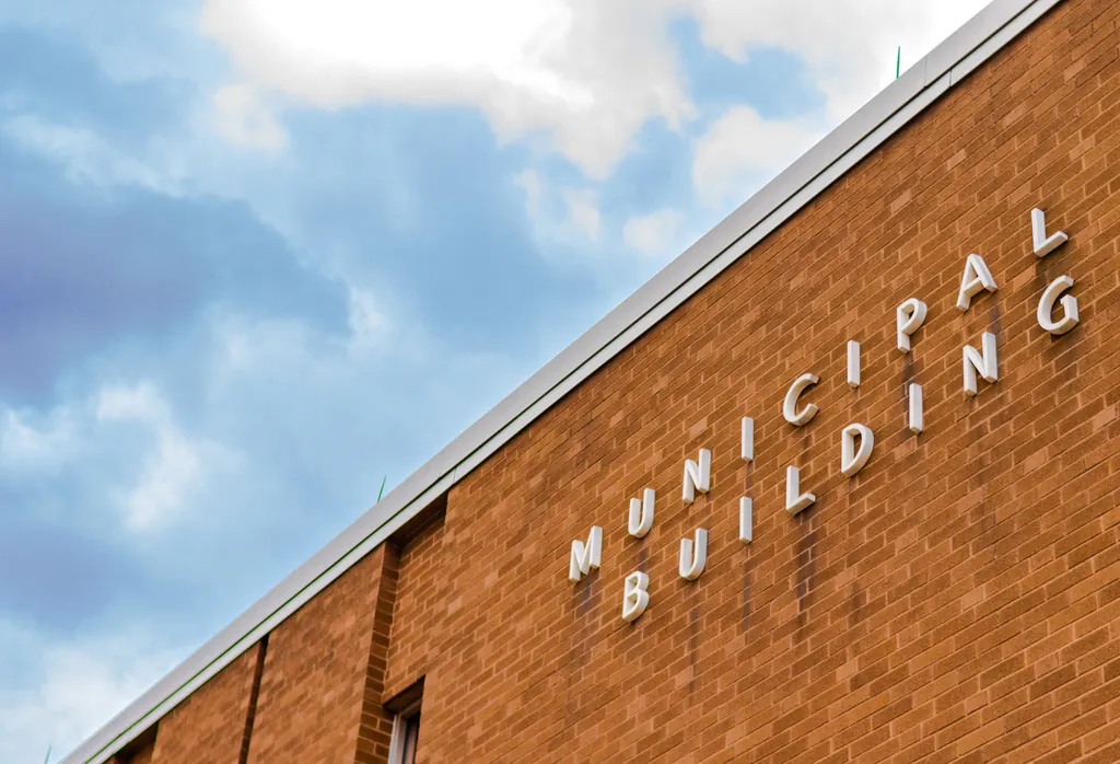 A face-brick municipal building with raised lettering under a cloudy sky